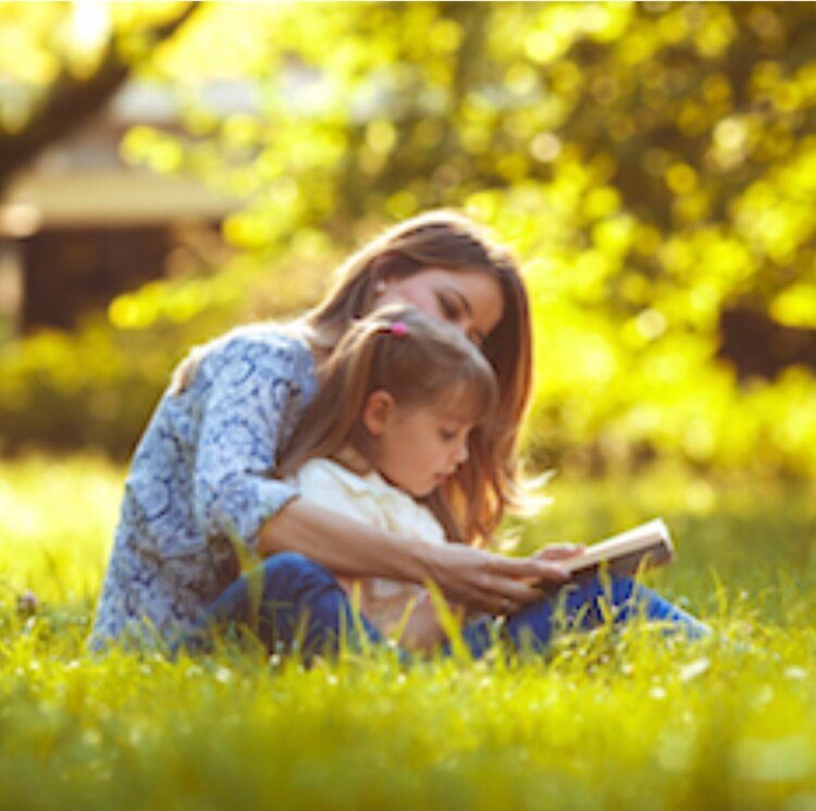 parent reading to her child in a field